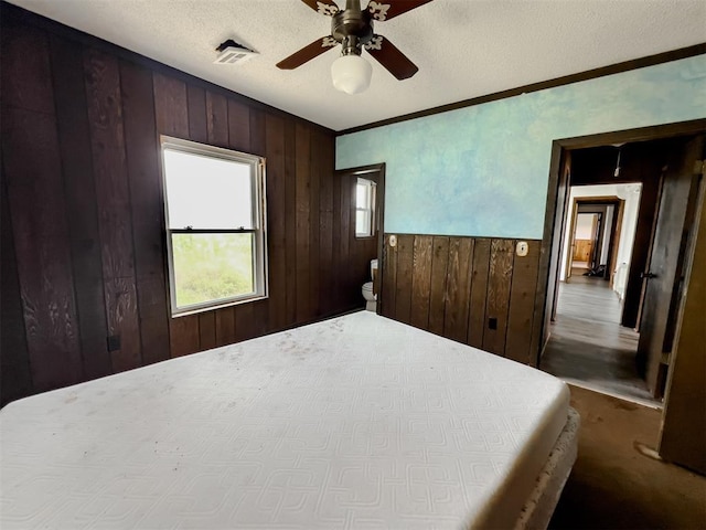 8701 Cornforth Rd, Guthrie, OK 73044 - bedroom featuring wooden walls, crown molding, ceiling fan, and a textured ceiling