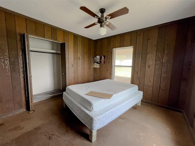 8701 Cornforth Rd, Guthrie, OK 73044 - bedroom featuring wooden walls, a closet, unfinished concrete floors, and ceiling fan