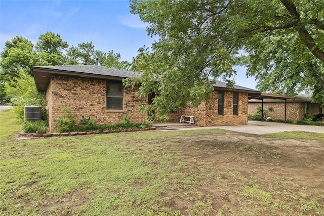 720 W 3rd St, Watonga, OK 73772 - view of front of house featuring central air condition unit, a front lawn, brick siding, and a carport