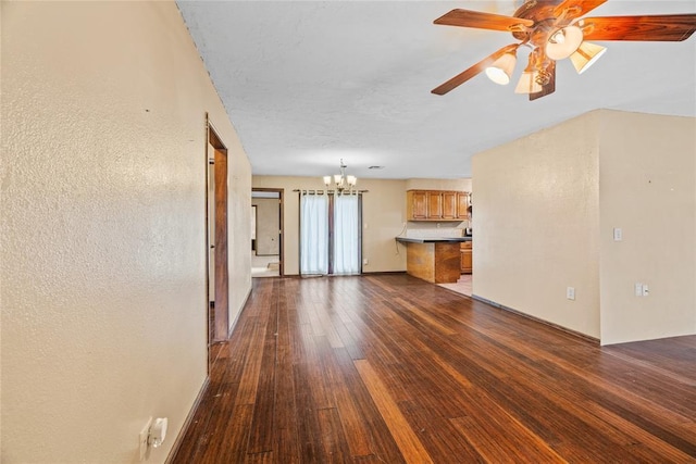 720 W 3rd St, Watonga, OK 73772 - unfurnished living room featuring a chandelier, ceiling fan, and dark wood-style floors