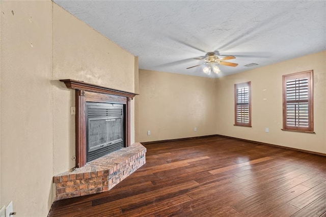 720 W 3rd St, Watonga, OK 73772 - unfurnished living room featuring a glass covered fireplace, a ceiling fan, wood-type flooring, a textured ceiling, and baseboards