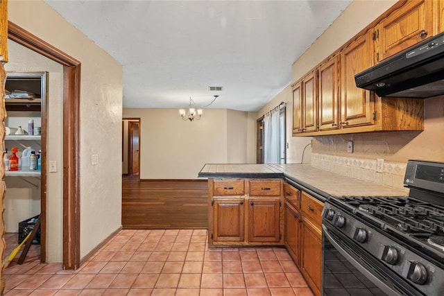 720 W 3rd St, Watonga, OK 73772 - kitchen featuring gas range, range hood, a peninsula, brown cabinets, and a chandelier