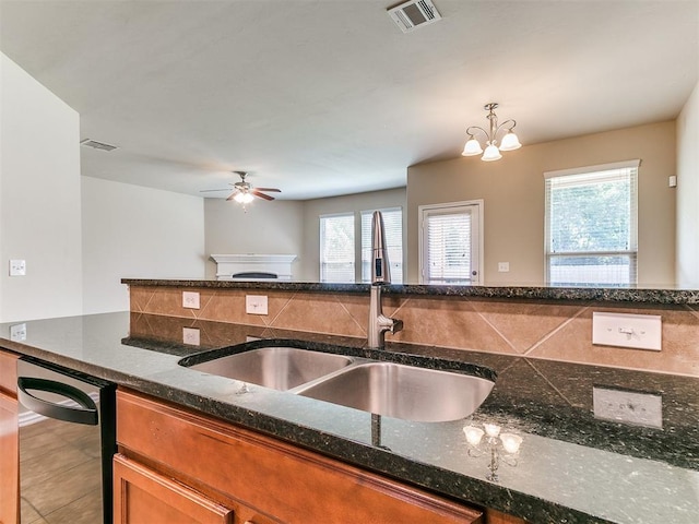 9708 Squire Ln, Yukon, OK 73099 - kitchen with plenty of natural light, brown cabinetry, a ceiling fan, and dark stone countertops