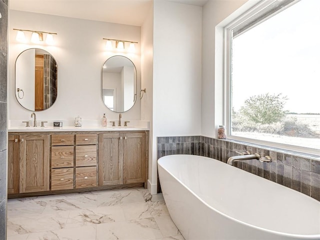 13133 Ashlyn Ln, Yukon, OK 73099 - bathroom featuring healthy amount of natural light, marble finish flooring, a freestanding bath, and double vanity