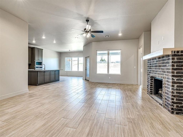 9608 Sultans Water Way, Yukon, OK 73099 - unfurnished living room with ceiling fan, a fireplace, light wood-style flooring, baseboards, and recessed lighting