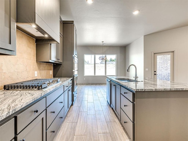 9608 Sultans Water Way, Yukon, OK 73099 - kitchen with a sink, stainless steel appliances, backsplash, a center island with sink, and light stone counters