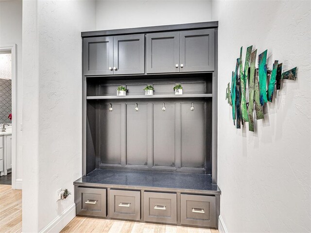 15825 Lacebark Ln, Edmond, OK 73013 - mudroom with light wood-type flooring, baseboards, and a textured wall