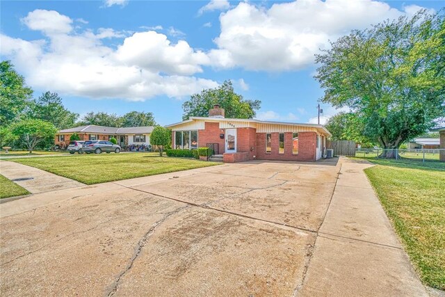 1909 N Flamingo Ln, Altus, OK 73521 - view of front of house with brick siding, concrete driveway, and a chimney