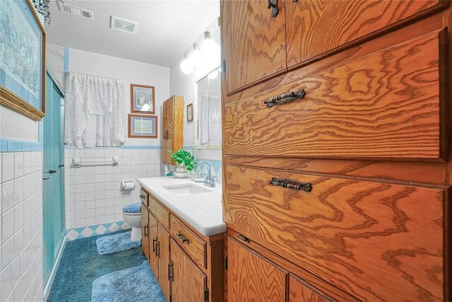 1909 N Flamingo Ln, Altus, OK 73521 - bathroom featuring vanity, toilet, tile walls, tile patterned flooring, and a wainscoted wall