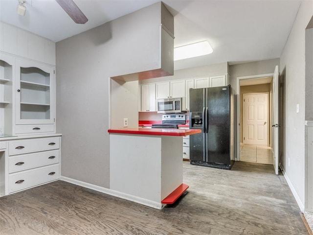 1505 W Blake St, El Reno, OK 73036 - kitchen with appliances with stainless steel finishes, wood finished floors, white cabinetry, a peninsula, and baseboards