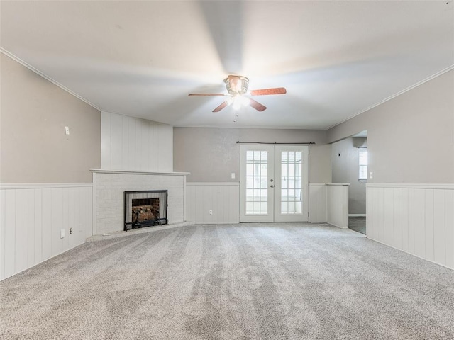 1505 W Blake St, El Reno, OK 73036 - unfurnished living room featuring a ceiling fan, a wainscoted wall, french doors, a brick fireplace, and crown molding