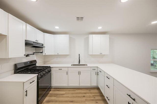 2817 N Donnelly Ave, Oklahoma City, OK 73107 - kitchen featuring black gas range oven, a sink, under cabinet range hood, white cabinetry, and recessed lighting