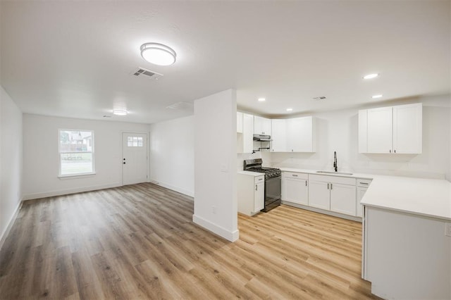 2817 N Donnelly Ave, Oklahoma City, OK 73107 - kitchen featuring range with gas stovetop, a sink, baseboards, light wood-style floors, and light countertops