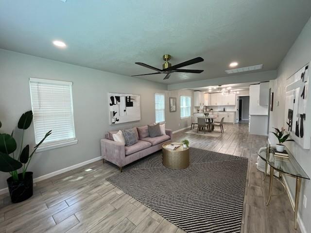 701 Iowa St, Norman, OK 73069 - living room featuring ceiling fan, baseboards, light wood finished floors, recessed lighting, and a chandelier