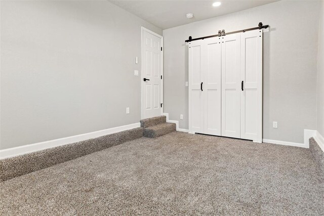 701 Iowa St, Norman, OK 73069 - unfurnished bedroom with carpet floors, a barn door, baseboards, and recessed lighting