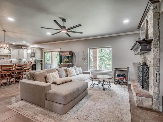 13505 Shady Pine Cir, Edmond, OK 73025 - living area featuring a stone fireplace, ceiling fan, ornamental molding, healthy amount of natural light, and tile patterned floors