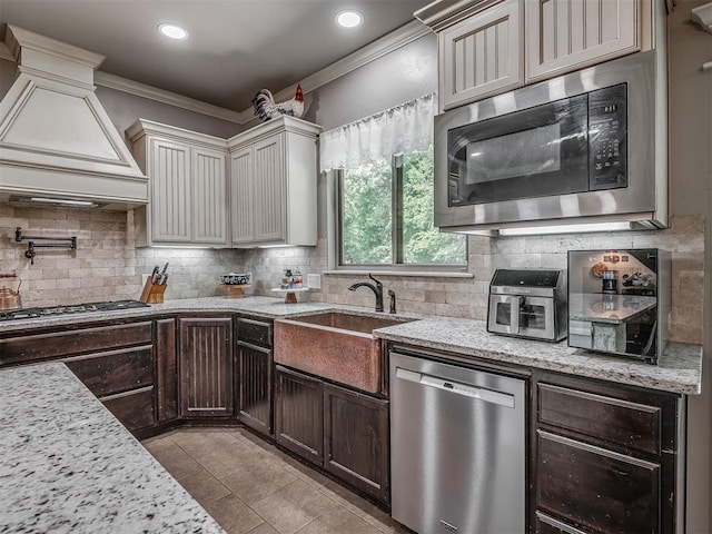 13505 Shady Pine Cir, Edmond, OK 73025 - kitchen featuring appliances with stainless steel finishes, a sink, wall chimney range hood, ornamental molding, and tasteful backsplash