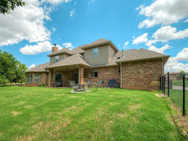 13505 Shady Pine Cir, Edmond, OK 73025 - back of house featuring brick siding, a chimney, a shingled roof, and a fire pit