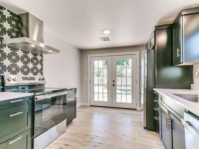 7624 NW 14th Ter, Oklahoma City, OK 73127 - kitchen featuring green cabinets, appliances with stainless steel finishes, wall chimney range hood, french doors, and light wood-style floors