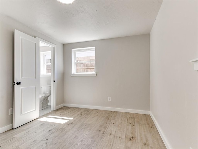 7624 NW 14th Ter, Oklahoma City, OK 73127 - unfurnished bedroom with wood finished floors, baseboards, and ensuite bath