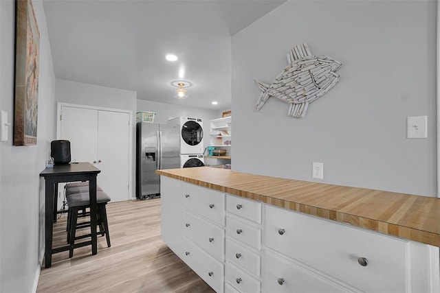109 Cowan Ave, Fort Cobb, OK 73038 - kitchen with stainless steel refrigerator with ice dispenser, stacked washing machine and dryer, white cabinets, light wood-style flooring, and butcher block counters