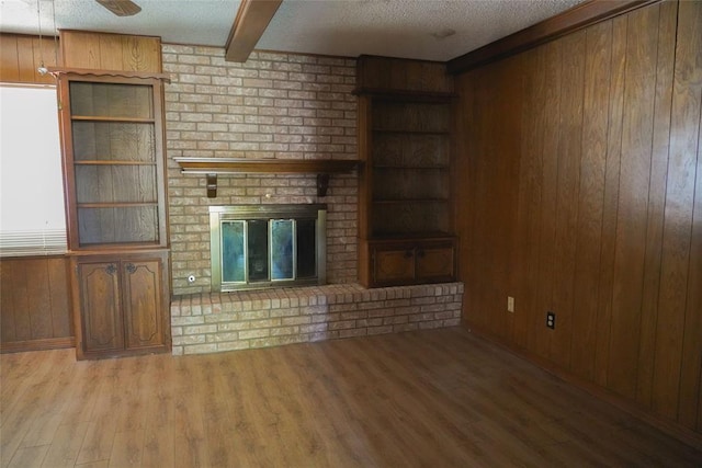 2313 SW 91st St, Oklahoma City, OK 73159 - unfurnished living room with wood walls, wood finished floors, a fireplace, a textured ceiling, and beam ceiling