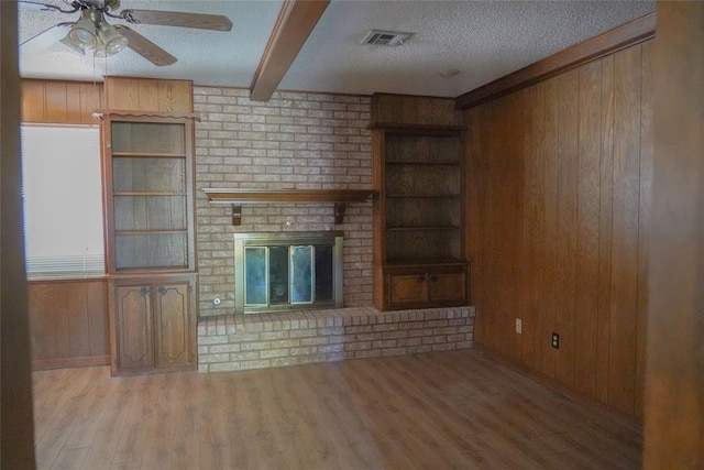 2313 SW 91st St, Oklahoma City, OK 73159 - unfurnished living room featuring wood walls, a ceiling fan, wood finished floors, beam ceiling, and a textured ceiling