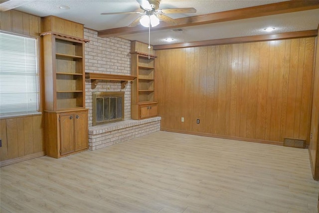 2313 SW 91st St, Oklahoma City, OK 73159 - unfurnished living room with beam ceiling, a ceiling fan, a textured ceiling, wooden walls, and light wood-style flooring