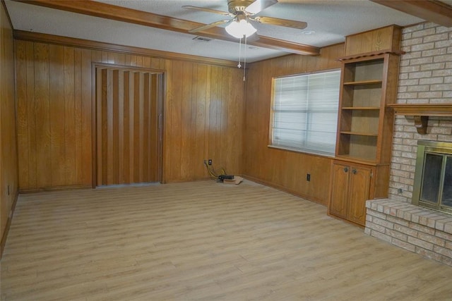 2313 SW 91st St, Oklahoma City, OK 73159 - unfurnished living room featuring a ceiling fan, beam ceiling, light wood-style flooring, a fireplace, and wood walls