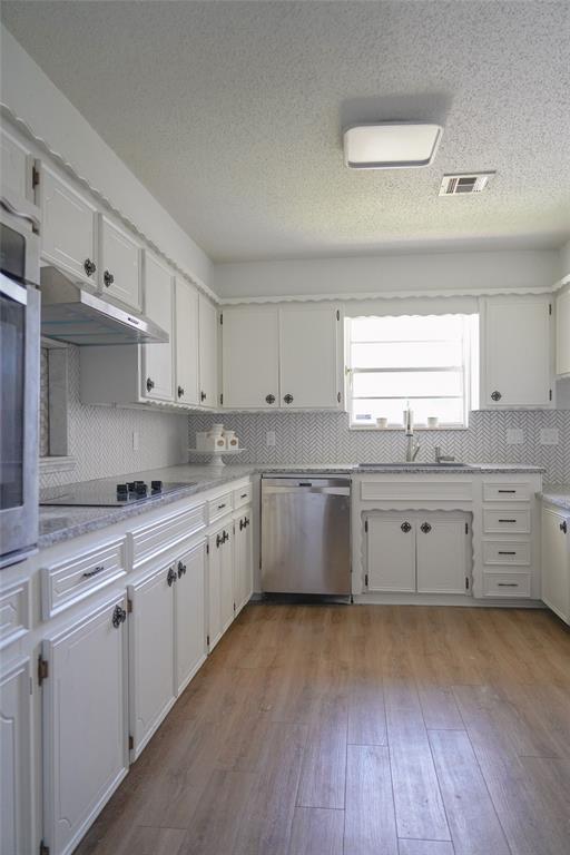 2313 SW 91st St, Oklahoma City, OK 73159 - kitchen featuring appliances with stainless steel finishes, under cabinet range hood, a sink, white cabinets, and a textured ceiling