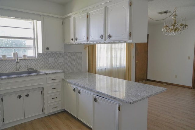 2313 SW 91st St, Oklahoma City, OK 73159 - kitchen with a sink, light wood finished floors, a peninsula, white cabinetry, and a chandelier
