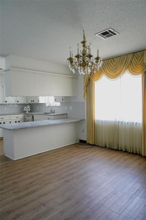 2313 SW 91st St, Oklahoma City, OK 73159 - kitchen with a chandelier, white cabinetry, tasteful backsplash, wood finished floors, and a sink