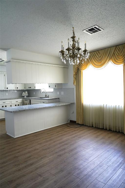 2313 SW 91st St, Oklahoma City, OK 73159 - kitchen with a chandelier, dark wood-style floors, white cabinetry, tasteful backsplash, and a textured ceiling