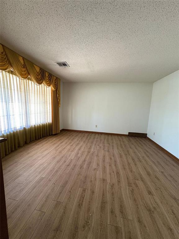 2313 SW 91st St, Oklahoma City, OK 73159 - spare room featuring wood finished floors, a textured ceiling, and baseboards