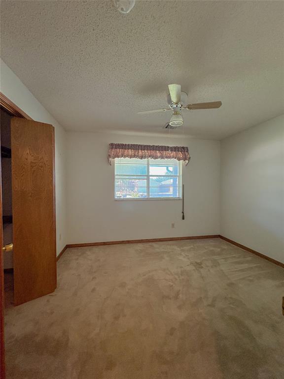 2313 SW 91st St, Oklahoma City, OK 73159 - unfurnished bedroom featuring light carpet, a textured ceiling, baseboards, and ceiling fan