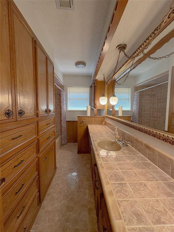 2313 SW 91st St, Oklahoma City, OK 73159 - full bath with vanity, a wainscoted wall, and a textured ceiling
