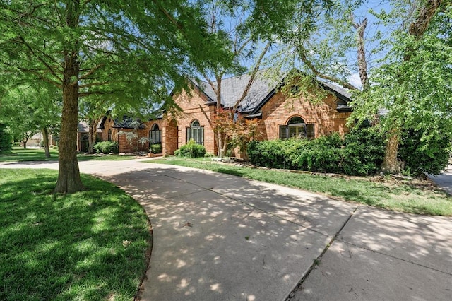 14705 Longford Way, Edmond, OK 73013 - tudor home featuring brick siding, a front yard, and curved driveway