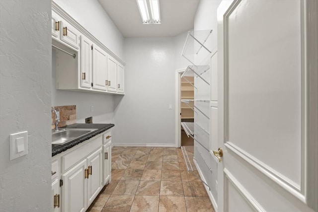 14705 Longford Way, Edmond, OK 73013 - laundry room featuring light stone finish floors, a sink, and baseboards