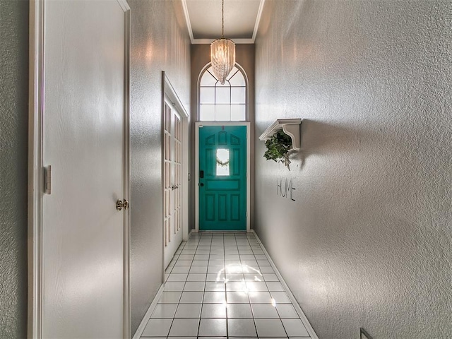 13005 Willowcrest Ln, Oklahoma City, OK 73170 - doorway to outside featuring light tile patterned floors, a textured wall, crown molding, a chandelier, and baseboards