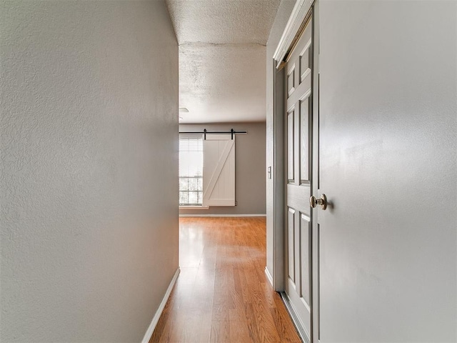 13005 Willowcrest Ln, Oklahoma City, OK 73170 - hall featuring baseboards, a barn door, light wood finished floors, and a textured ceiling