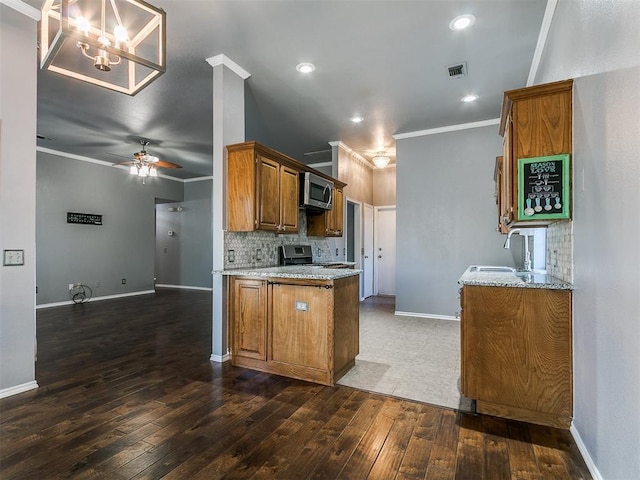 13005 Willowcrest Ln, Oklahoma City, OK 73170 - kitchen with stainless steel appliances, crown molding, brown cabinets, light stone countertops, and wood-type flooring