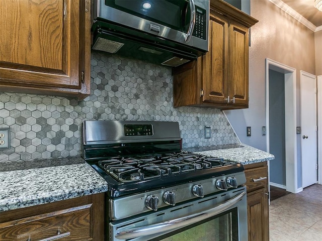 13005 Willowcrest Ln, Oklahoma City, OK 73170 - kitchen featuring stainless steel appliances, crown molding, tasteful backsplash, light tile patterned flooring, and light stone counters