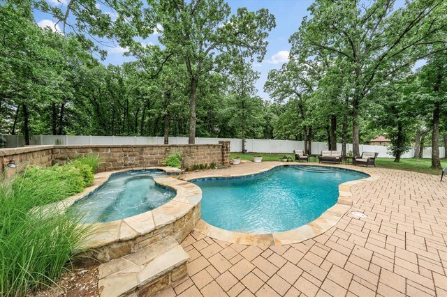 910744 S 3440th Rd, Chandler, OK 74834 - view of swimming pool featuring a patio, a fenced backyard, a pool with connected hot tub, and view of wooded area