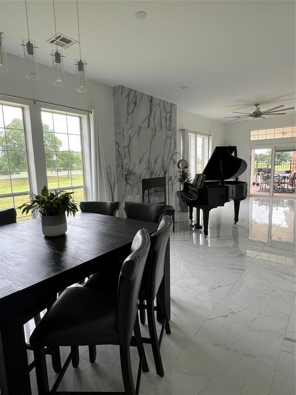 1030 Belmonte Ct, Yukon, OK 73099 - dining area featuring light marble finish floors, ceiling fan, and a large fireplace