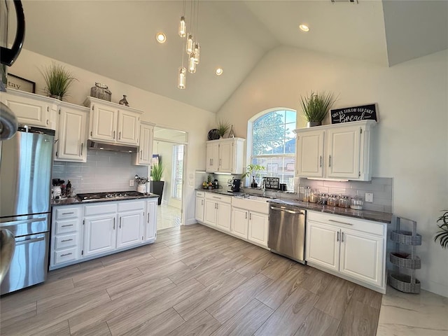 1030 Belmonte Ct, Yukon, OK 73099 - kitchen featuring appliances with stainless steel finishes, dark countertops, under cabinet range hood, white cabinets, and lofted ceiling