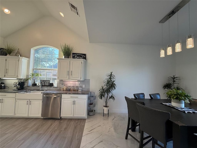 1030 Belmonte Ct, Yukon, OK 73099 - kitchen featuring stainless steel dishwasher, dark countertops, a sink, lofted ceiling, and backsplash
