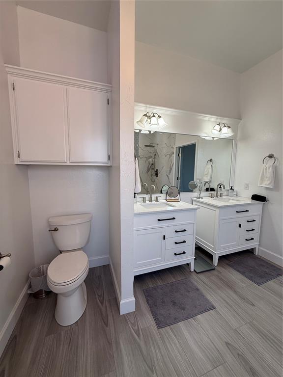 1030 Belmonte Ct, Yukon, OK 73099 - bathroom with two vanities, baseboards, toilet, and wood finished floors