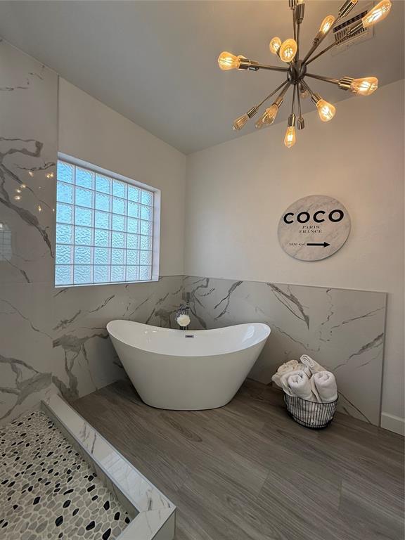 1030 Belmonte Ct, Yukon, OK 73099 - full bathroom with a chandelier, a freestanding tub, a wainscoted wall, a marble finish shower, and tile walls