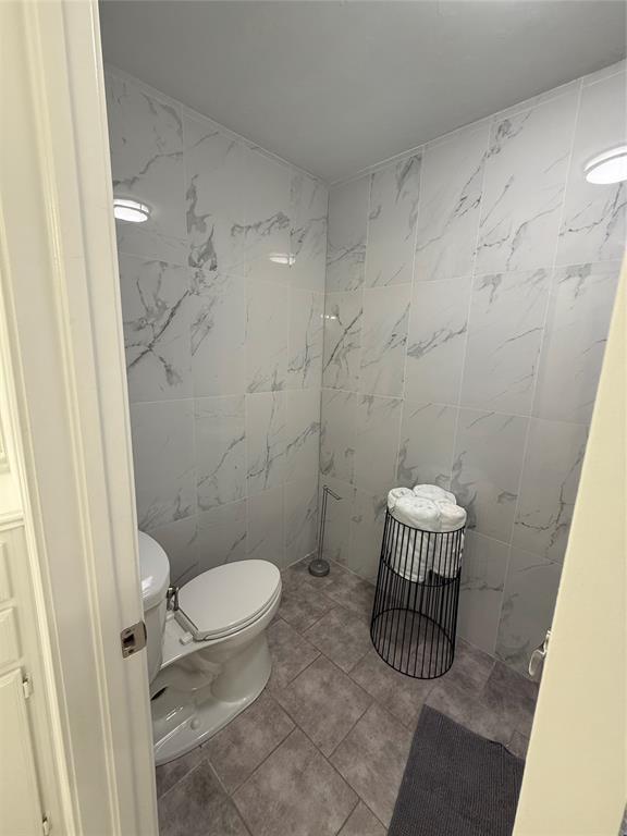 1030 Belmonte Ct, Yukon, OK 73099 - bathroom with tile walls, toilet, and tile patterned flooring