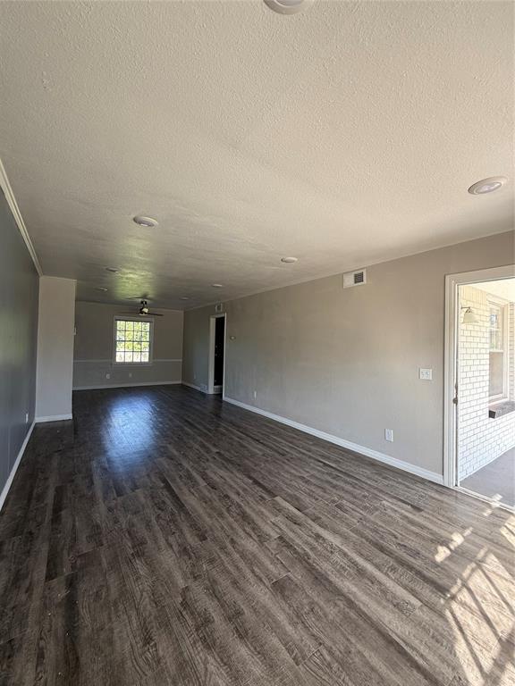 3208 N Roff Ave, Oklahoma City, OK 73112 - unfurnished living room with a textured ceiling, dark wood-style flooring, and baseboards